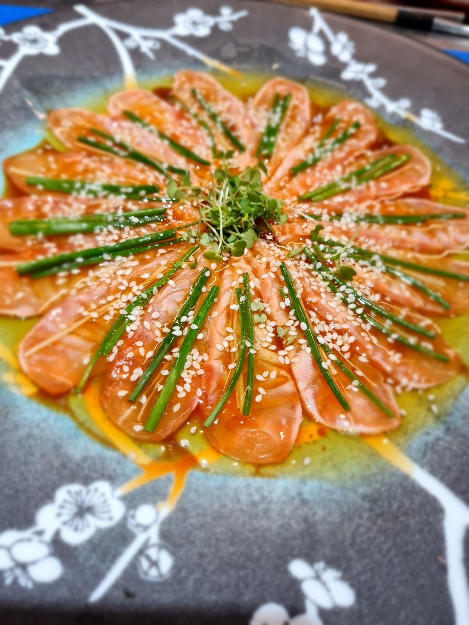 Salmon ceviche sliced into a rosette, in a citrus-chilli dressing with chives, sesame and micro greens.