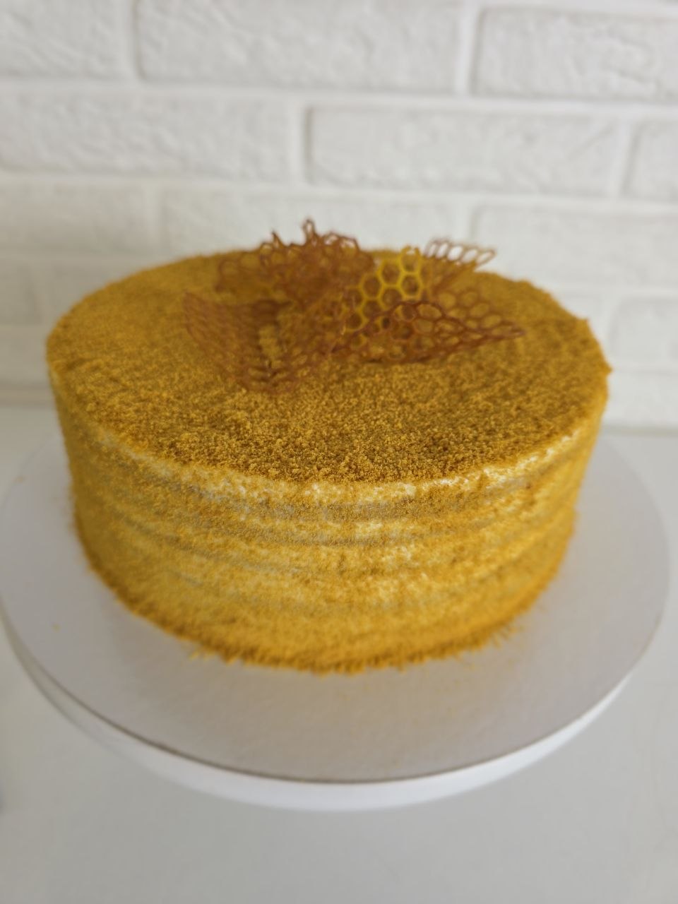 A whole layered honey cake (Medovik) coated in honey-sponge crumb and decorated with caramel honeycomb.